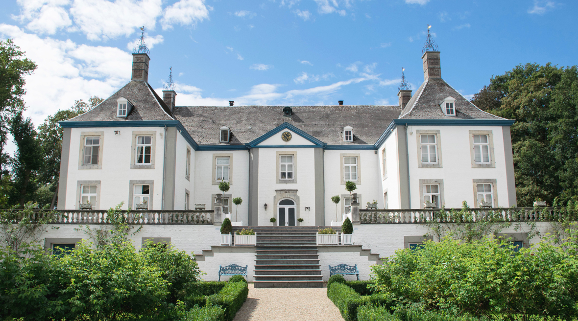 Large symmetrical white estate building with grey roof and terraced garden